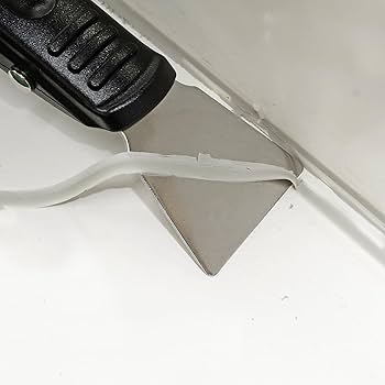 Removing old caulk with a scraper.